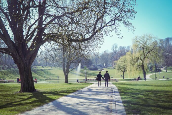 Photo by Markus Freise two people walking down a path in a park