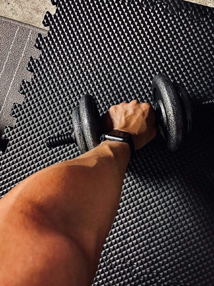 person wearing black and white shirt holding black dumbbell