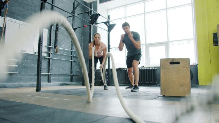 Man and woman exercising with battle ropes.