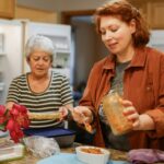 생활 속 니트(NEAT) 다이어트: 헬스장 밖에서도 칼로리를 태우는 일상 활동의 위력 Two women preparing food in a kitchen.