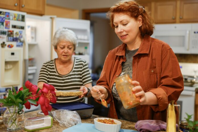 Two women preparing food in a kitchen.