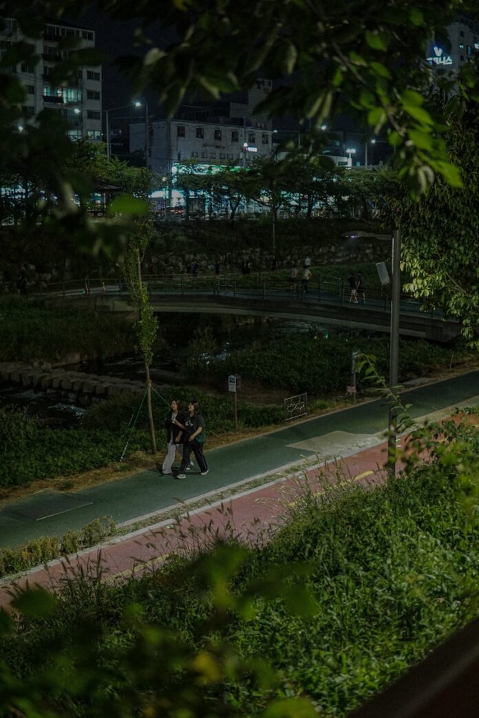 Photo by jieun kim a couple of people walking down a street at night