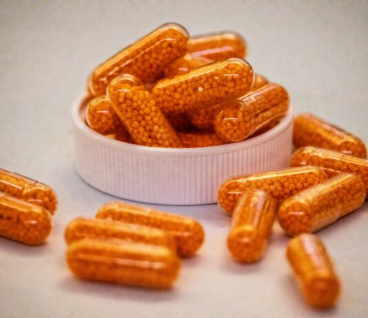 비타민과 영양제: “다 먹어야 할까?” 운동인이 꼭 챙겨야 할 필수 영양소 Top 3 Orange capsules filled with small beads spill from container.
