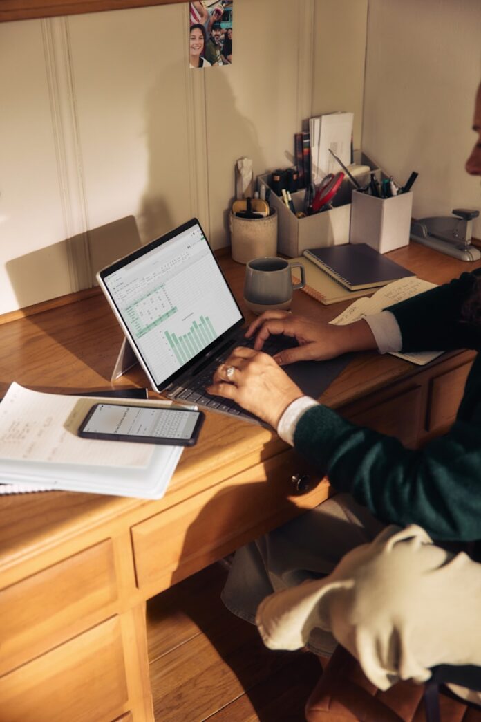 Person working on laptop at a wooden desk.