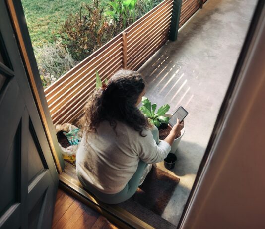 만성피로, ‘느리게 살아보기’가 해답일까?…실천 가능한 일상 회복 루틴 주목 Woman sitting on balcony with smartphone