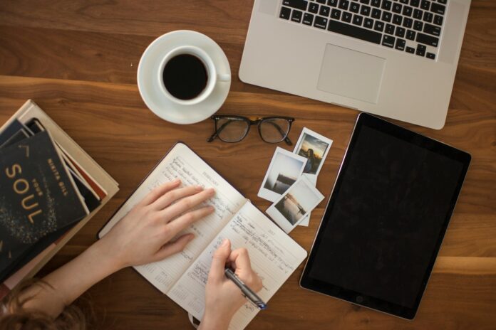 Photo by Thought Catalog person holding ballpoint pen writing on notebook