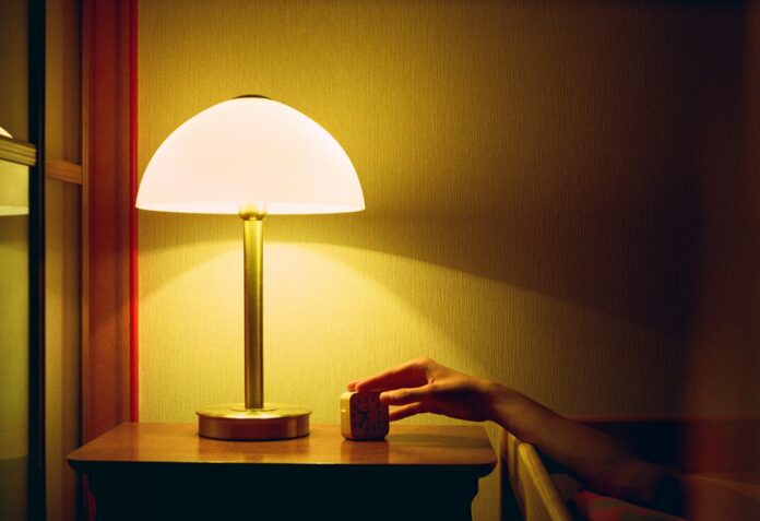 Photo by Mykyta Kravčenko a person's hand on a table next to a lamp