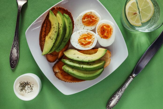Photo by Elena Leya a white plate topped with eggs and avocado