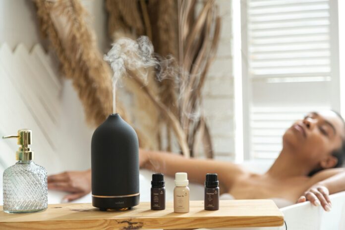 Photo by volant a woman laying in a bathtub next to a bottle of essential oils