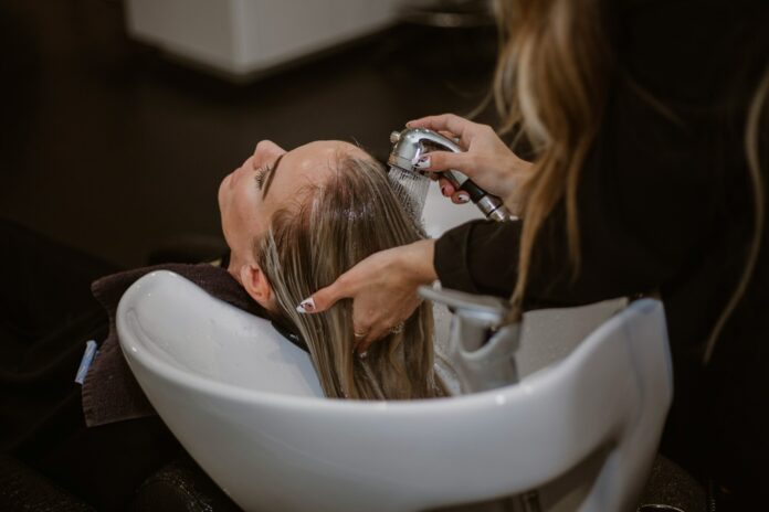 Photo by Lindsay Cash a woman getting her hair cut by a hair stylist