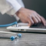 “AI, 우리 집 건강 지킴이로”…일상에 녹아든 스마트 건강 관리법 Doctor typing on a laptop with a stethoscope nearby.