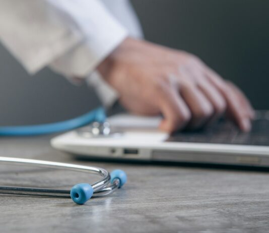 “AI, 우리 집 건강 지킴이로”…일상에 녹아든 스마트 건강 관리법 Doctor typing on a laptop with a stethoscope nearby.