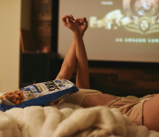 ‘저녁 8시 이후 금식’… 최근 떠오르는 ‘마지막 식사 시간 지키기’ 건강습관 인기 a person laying on a bed with a bag of popcorn