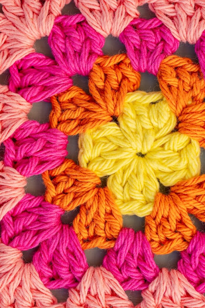 Vibrant crochet granny square pattern in yellow, orange, and pink.