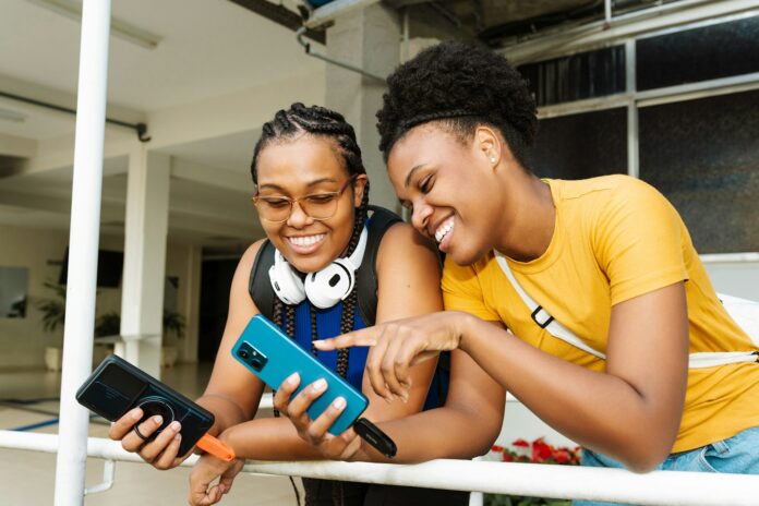 Photo by Sandisk Two smiling women looking at a smartphone together.