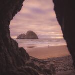 바쁜 일상 속 스트레스, 똑똑하게 풀고 건강 챙기는 생활 습관 Sea stack and beach visible through a dark cave opening.