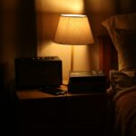 수면 혁명, 내 일상 속 꿀잠 길들이기…지금 실천할 수 있는 수면 건강 트렌드 A bedside lamp illuminates a nightstand with a radio.