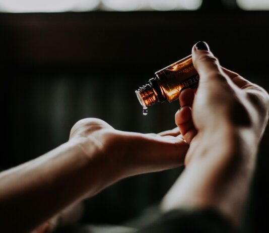 ‘슬기로운 헤어케어’… 건강한 모발을 위한 일상 속 실천법 person holding amber glass bottle