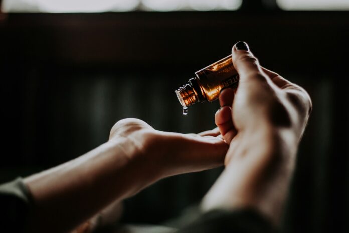 Photo by Christin Hume person holding amber glass bottle
