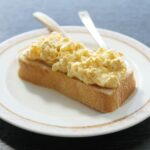 “마음챙김 식사법, 바쁜 한국인의 건강한 일상 열쇠로 부상” A piece of bread topped with scrambled eggs on a white plate