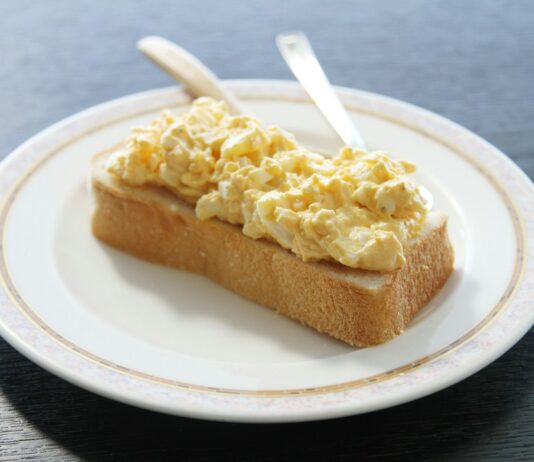 “마음챙김 식사법, 바쁜 한국인의 건강한 일상 열쇠로 부상” A piece of bread topped with scrambled eggs on a white plate