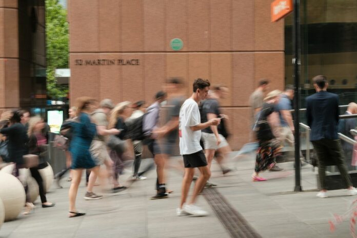 Photo by Dominic Kurniawan Suryaputra A crowd of people walking down a street next to a tall building
