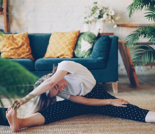 아침 루틴, 건강을 바꾸다… “작은 습관부터 시작하세요” Woman stretching on floor in a living room.