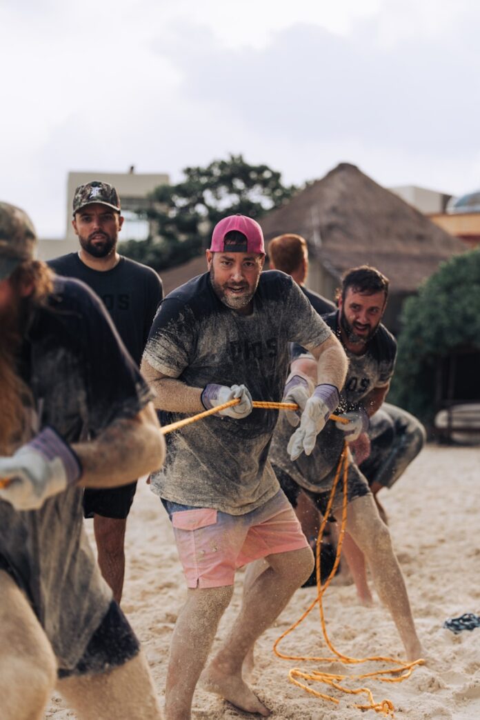 Men playing tug-of-war on a sandy beach