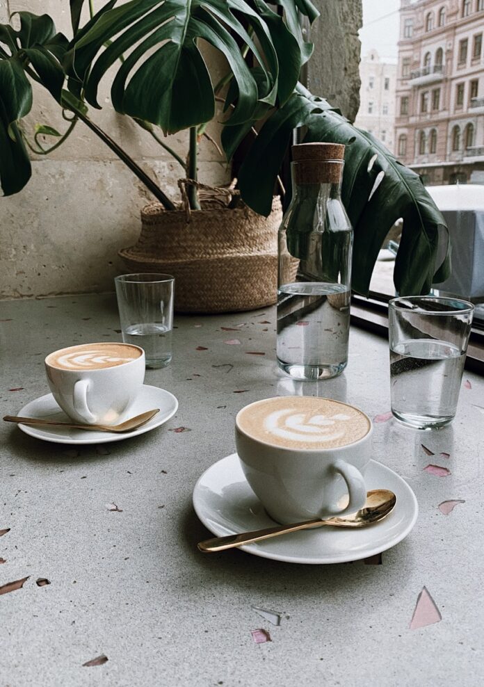 Photo by Masha Kotliarenko clear glass bottle near cappucino