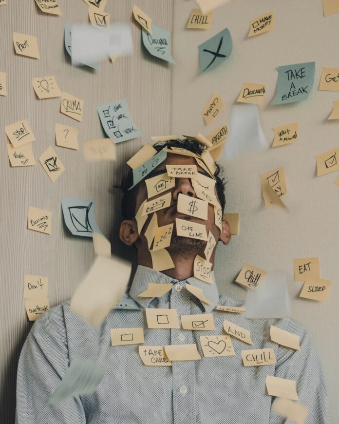 Photo by Luis Villasmil man covered in sticky notes at office desk