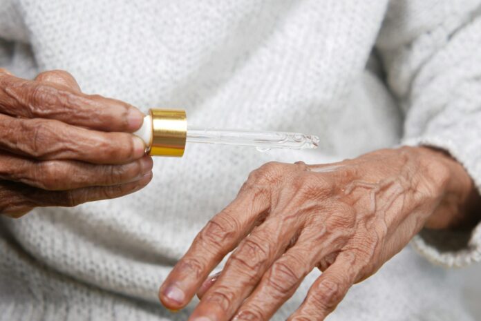 Photo by Towfiqu barbhuiya an older woman holding a small tube of liquid