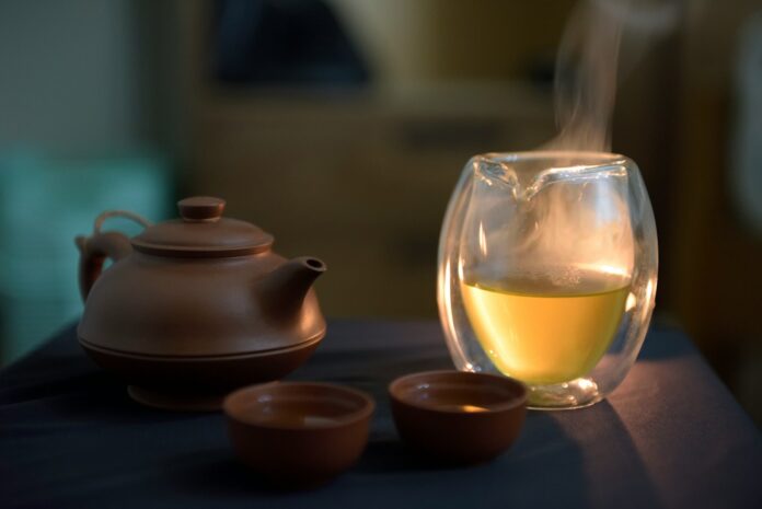 Photo by Max Chen a glass of white wine next to a tea pot