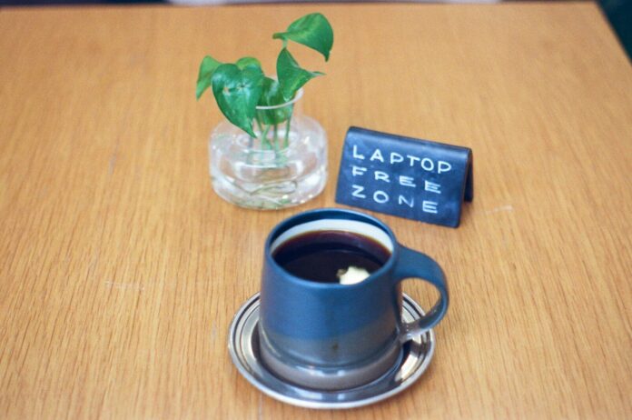 Photo by Bradley Andrews A mug of coffee with a plant and sign