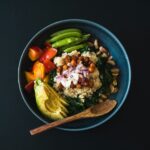 건강한 식습관, ‘한 그릇 밥상’에서 시작하는 소소한 변화 a blue bowl filled with vegetables and a wooden spoon