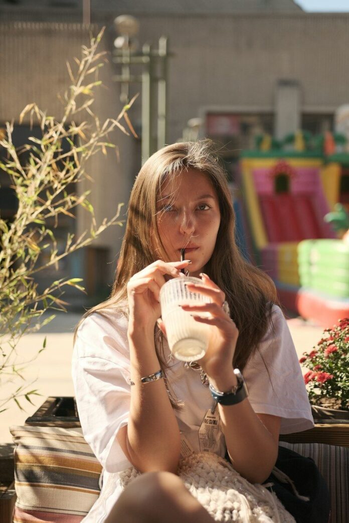 Photo by Anton Luk Woman sips a drink on a sunny outdoor patio