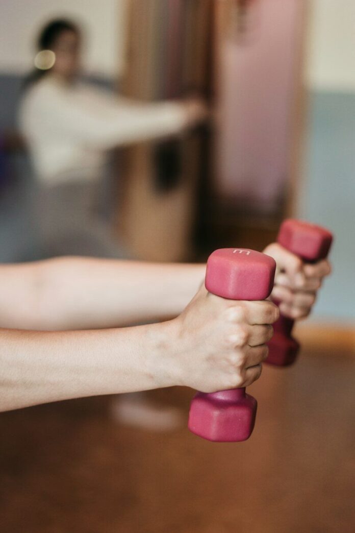 Photo by Juls P person holding pink and white dumbbells