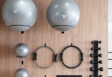 “필라테스, 일상에 녹여 더 건강하게…한국인 맞춤 실천법 인기” Gym equipment neatly organized on a wooden wall
